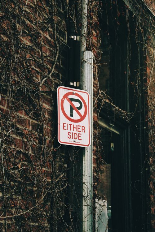 Free Brick wall with no parking sign surrounded by vines, creating a vintage street vibe. Stock Photo