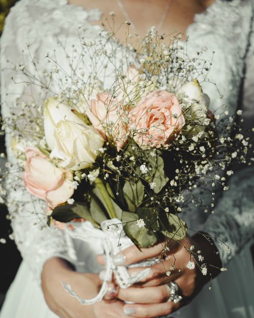 Free Crop anonymous elegant woman in bridal dress and rings with rose bouquet during festive event Stock Photo