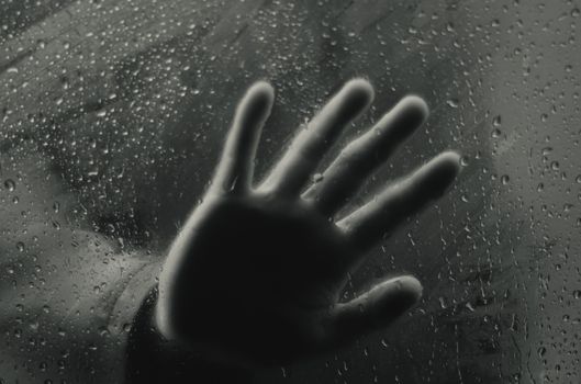 一只手按在雨水浸湿的窗上，孤独与神秘感随之涌起