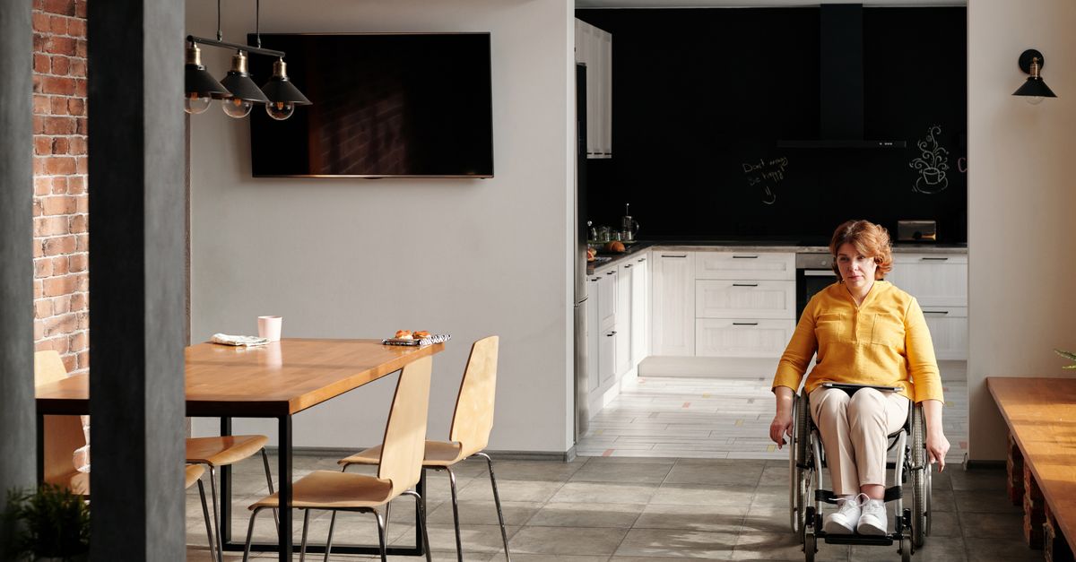 A woman in a wheelchair sits in a modern kitchen, showcasing accessibility in home design.