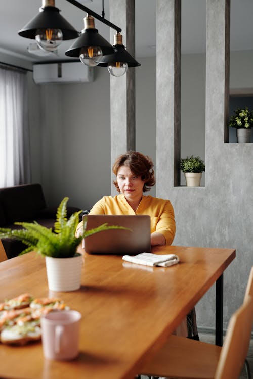 Free Woman in Yellow Long Sleeve Shirt Typing on Her Laptop Stock Photo