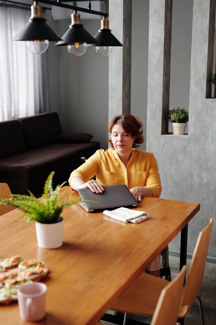 Woman In Yellow Long Sleeve Shirt Finish Working On Her Laptop