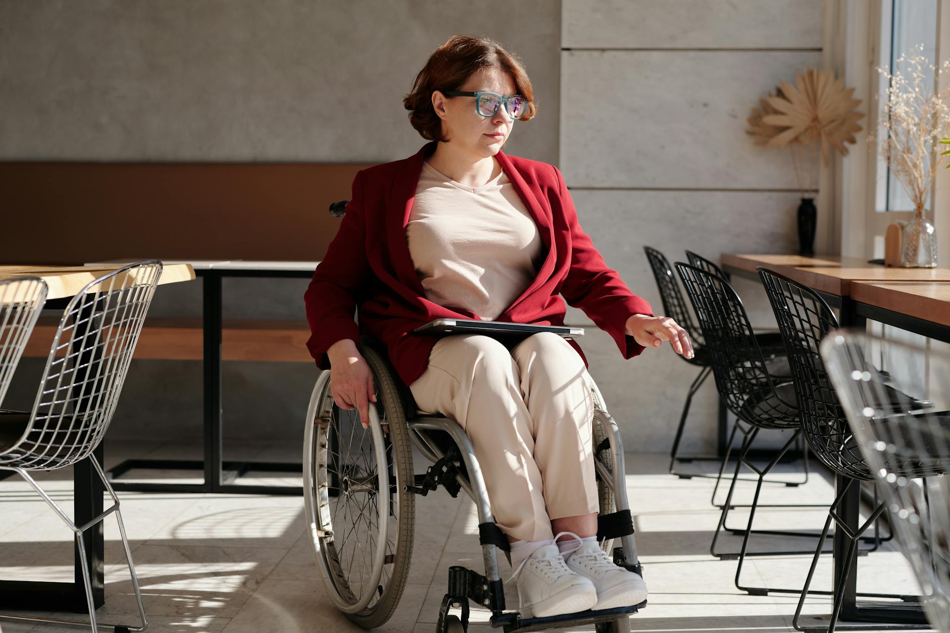 Stylish woman in wheelchair inside a brightly lit café, showcasing accessibility and lifestyle.