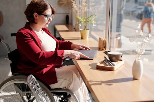 Woman in Red and White Long Sleeve Shirt Sitting on Wheelchair