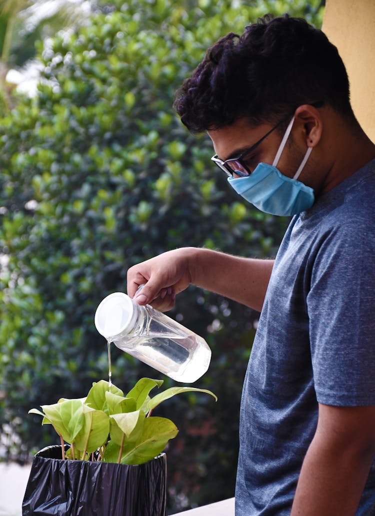 Man In Blue Crew Neck T-shirt Watering The Plant