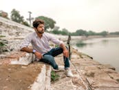 一个放松的人若有所思地坐在风景秀丽的湖边石阶上，凝视着远方