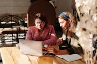 两名妇女在舒适的咖啡馆里一起用笔记本电脑工作