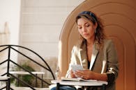 女商人坐在室内，沐浴着阳光，用着智能手机和笔记本