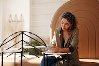 穿西装外套的女人在现代室内环境中使用智能手机写笔记