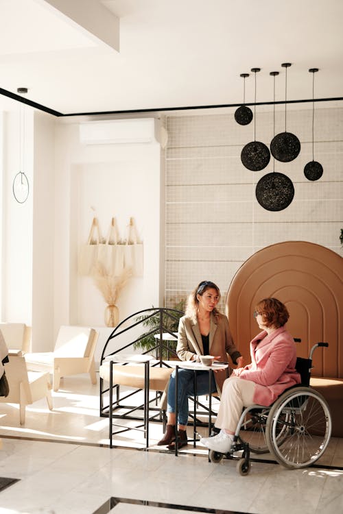 A Woman in a Wheelchair Talking to Another Woman