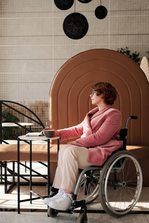 Woman in Pink Sweater Sitting on Black Wheelchair