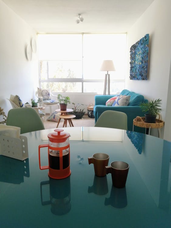Glass table with cups and tea placed in cozy living room near couch