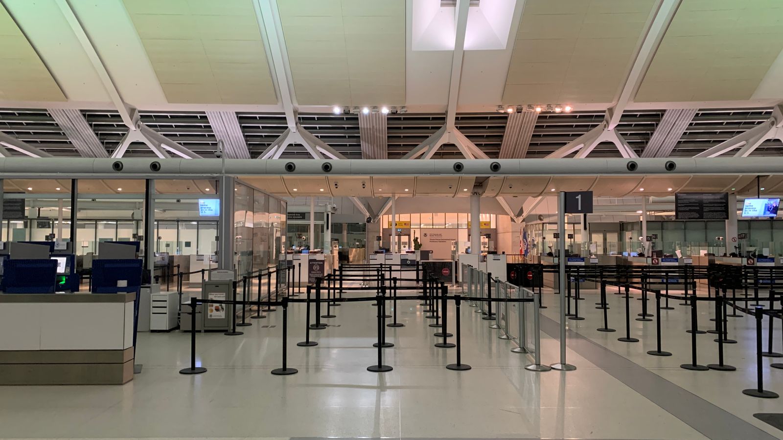 Empty check-in area of a modern airport with sleek design and organized layout.