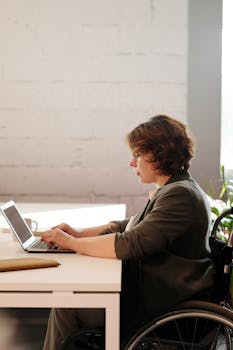 一位专注于轮椅业务的女商人正在现代家庭办公室的笔记本电脑前工作