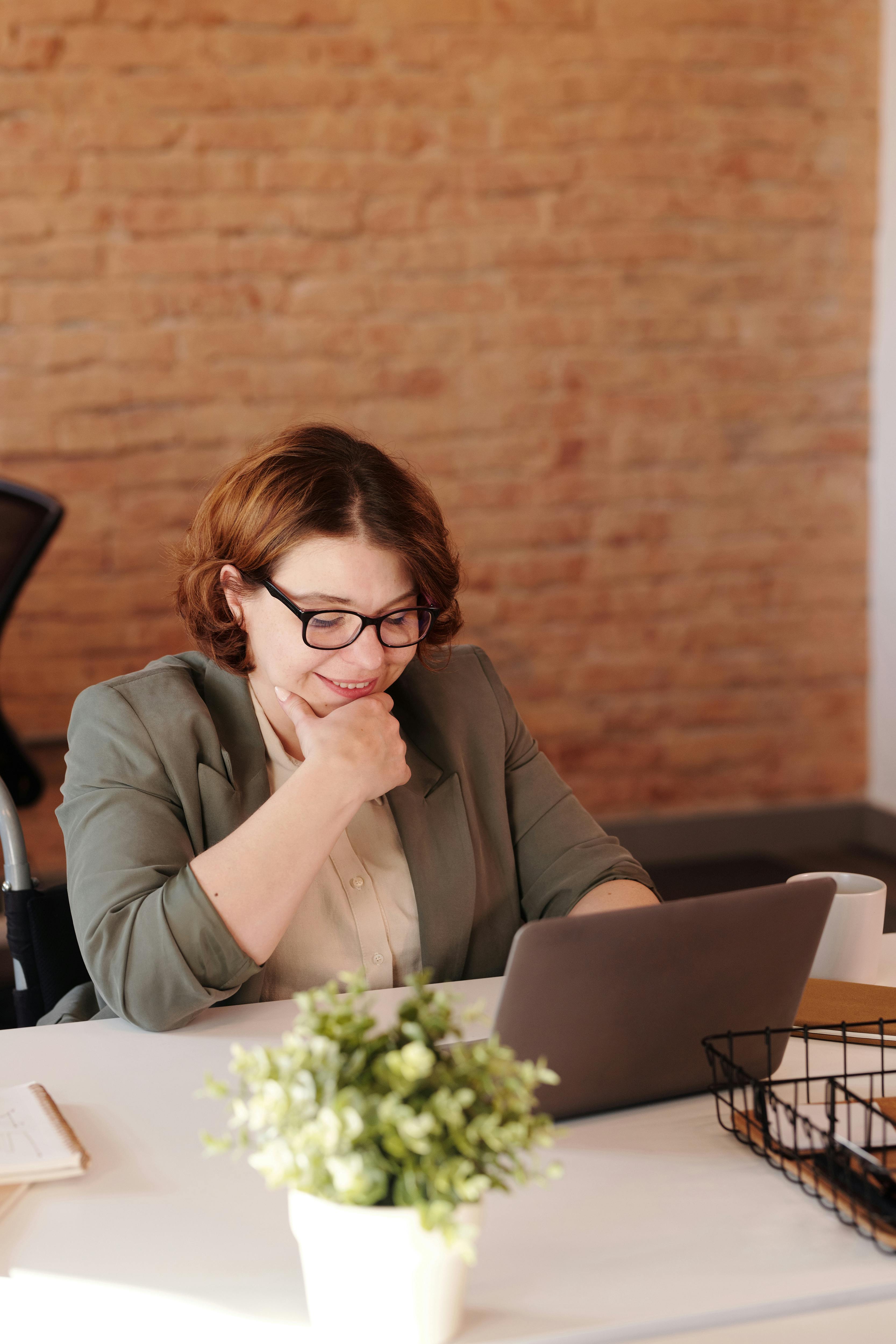 photo of woman smiling while using laptop