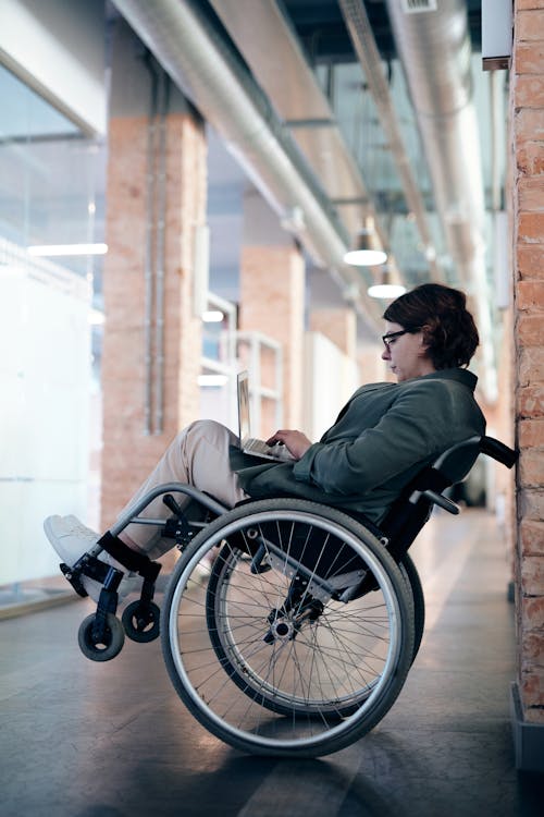 Woman Sitting on Wheelchair While Using Laptop
