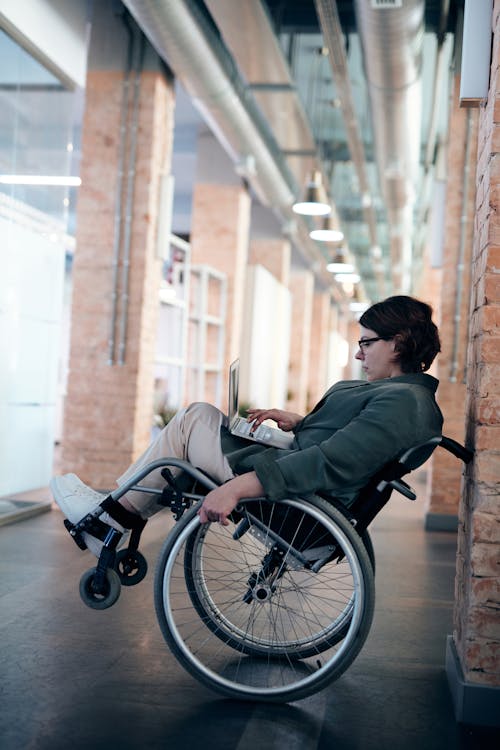 Free Woman Sitting on Wheelchair While Using Laptop Stock Photo