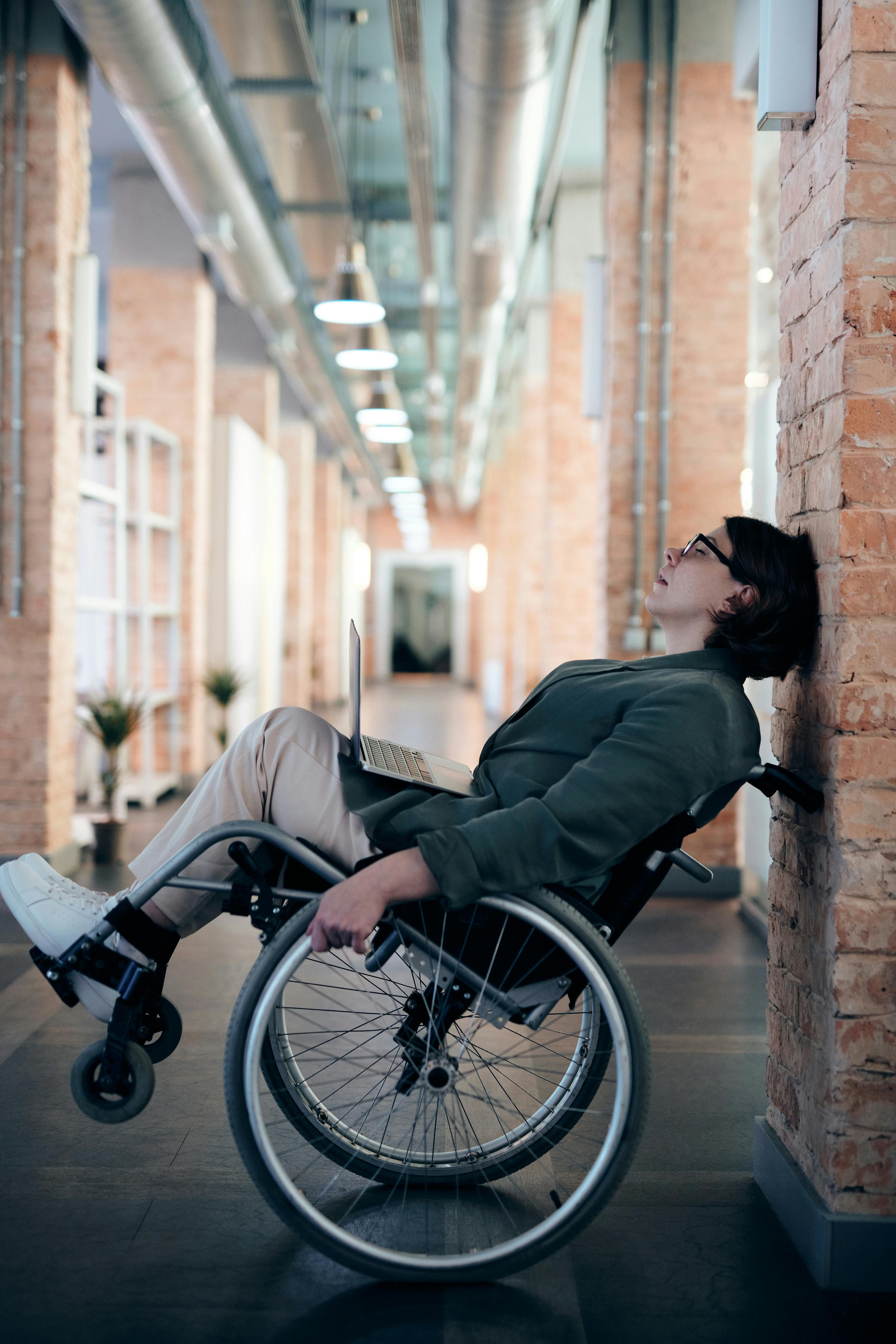 woman sitting on wheelchair while leaning on wall