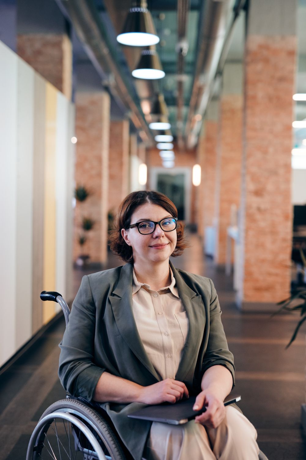Femme professionnelle en fauteuil roulant souriante dans un bureau moderne et inclusif