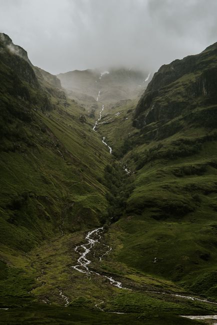 A breathtaking view of a misty highland valley in Scotland with a flowing river.