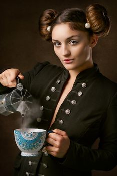 一位身穿黑色外套的女人将热气腾腾的咖啡从水罐倒进装饰用的杯子里