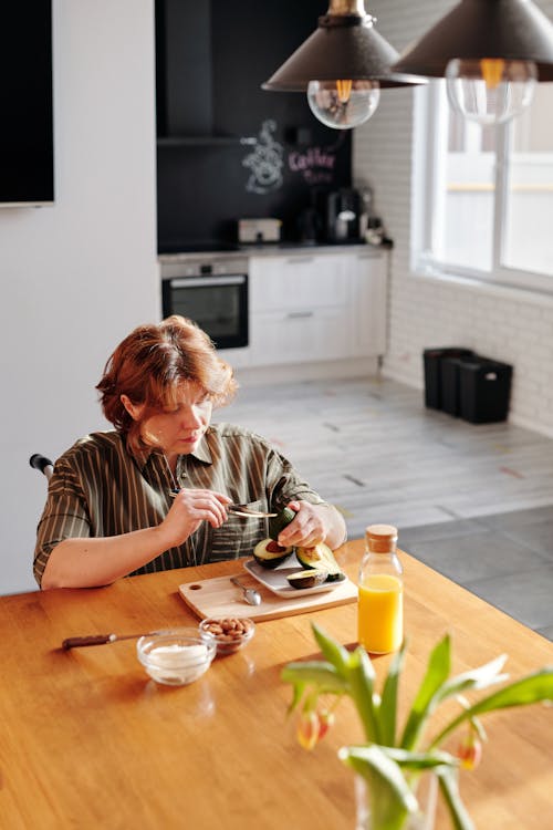 Woman in Black and White Stripe Shirt Sitting by the Table