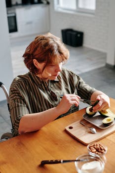 Adult woman cutting avocados at home, highlighting healthy eating and independence.