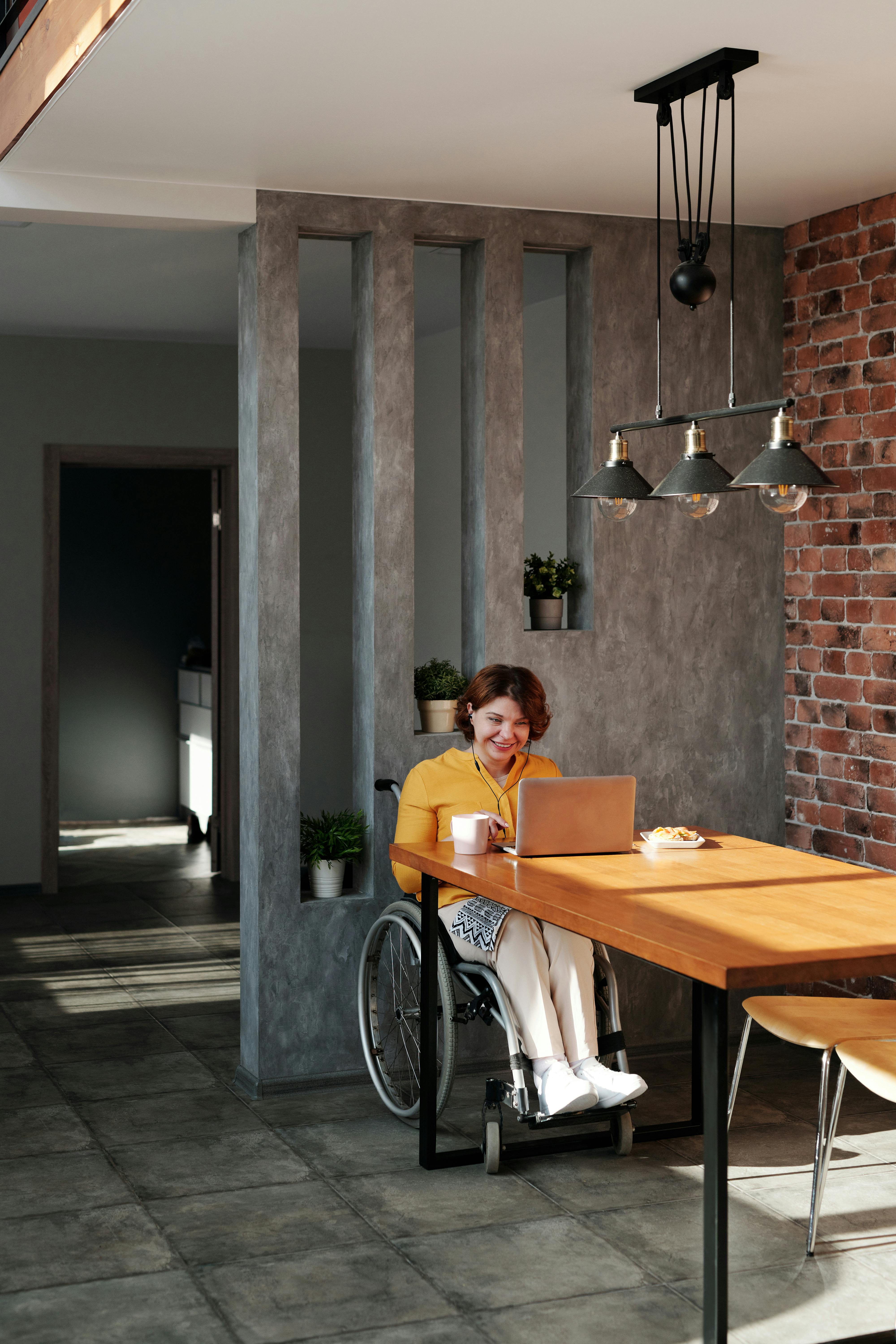 woman sitting on wheelchair while using laptop