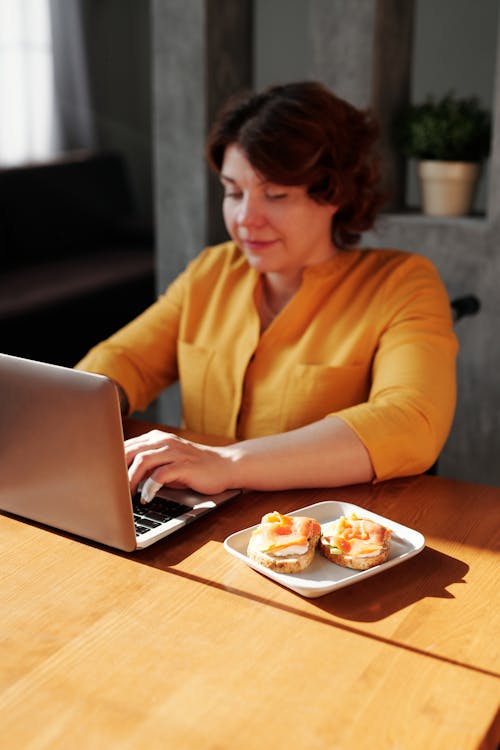 Woman in Orange Long Sleeve Shirt Using Macbook Pro