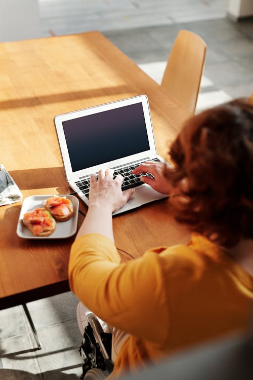 Free Woman in Yellow Long Sleeve Shirt Using Macbook Air Stock Photo
