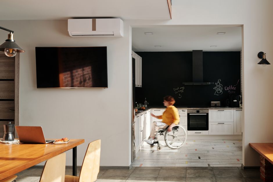A woman in a wheelchair moves quickly through a modern kitchen with sleek design elements.
