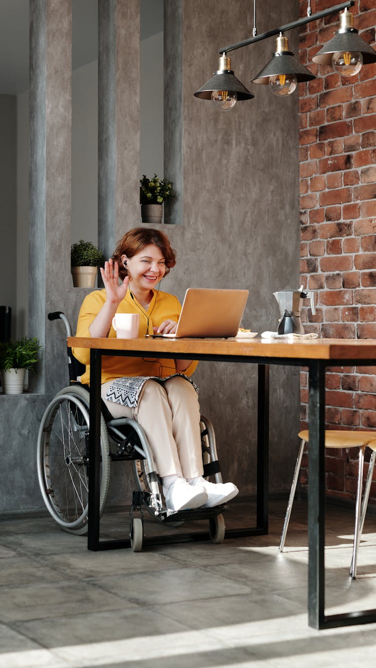 Woman Sitting On Wheelchair Using Laptop