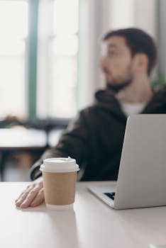 Young man working from home with laptop and coffee, a perfect work-from-home setup.