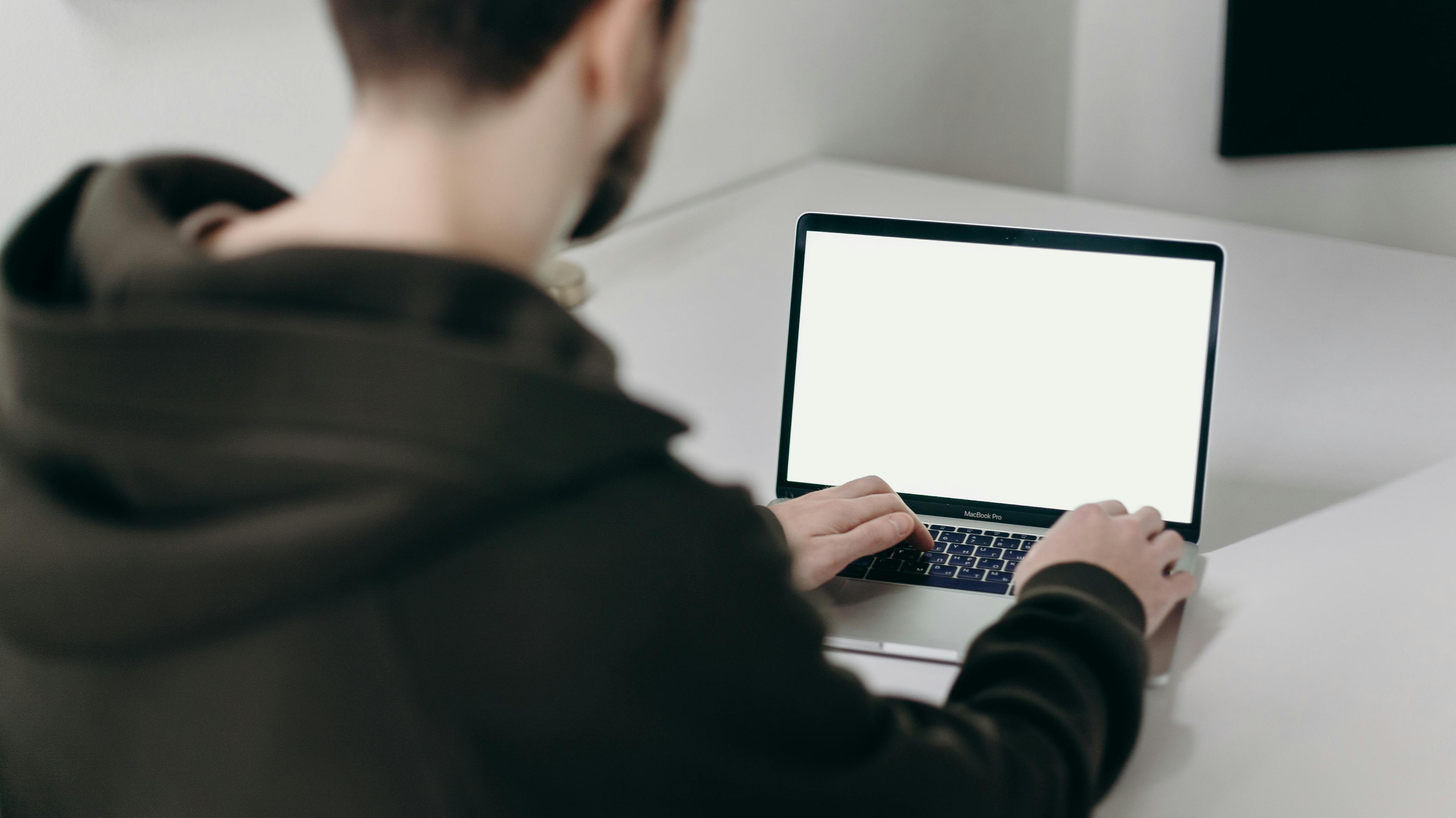 man in black jacket using macbook pro