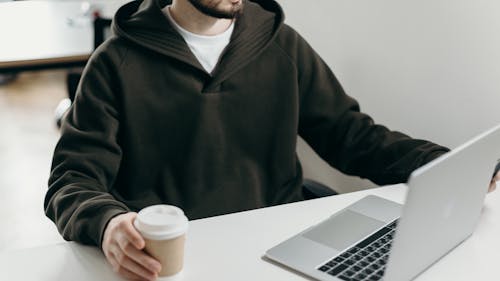 Man in Black Zip Up Jacket Holding White Disposable Cup