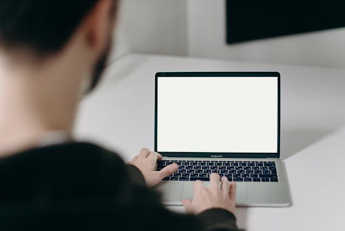 Free Person Using Macbook Pro on White Table Stock Photo