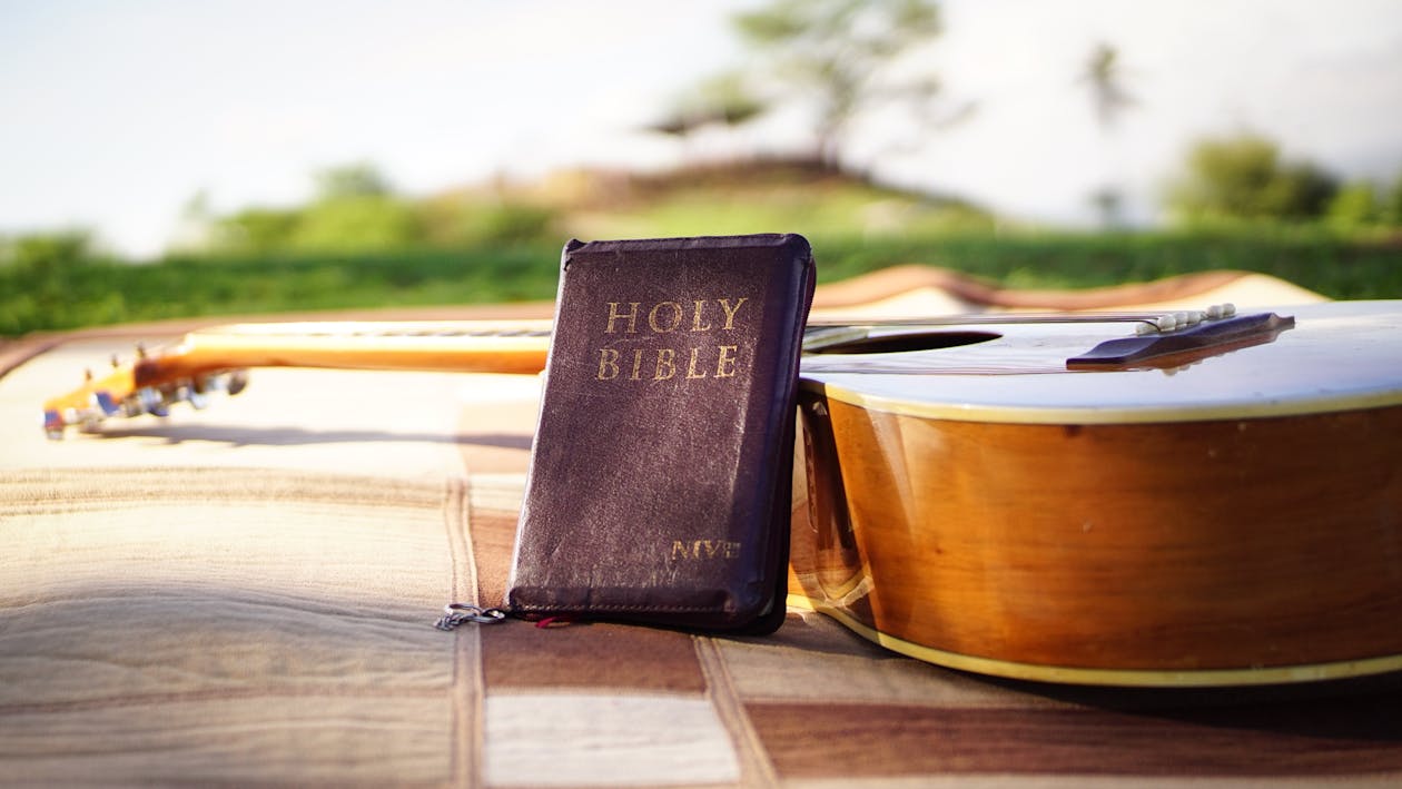 Photo of Holy Bible Near Acoustic Guitar