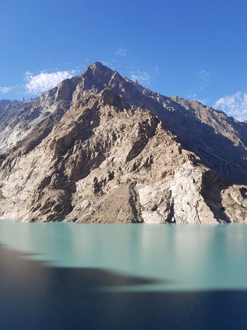 Free Beautiful clear waters of Attabad Lake in Hunza Valley with rocky mountain backdrop under blue sky. Stock Photo