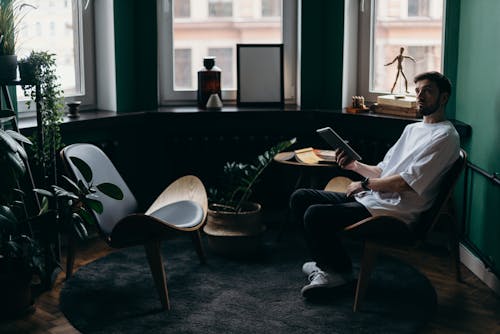 Photo of Man Wearing White T-Shirt While Holding an Ipad