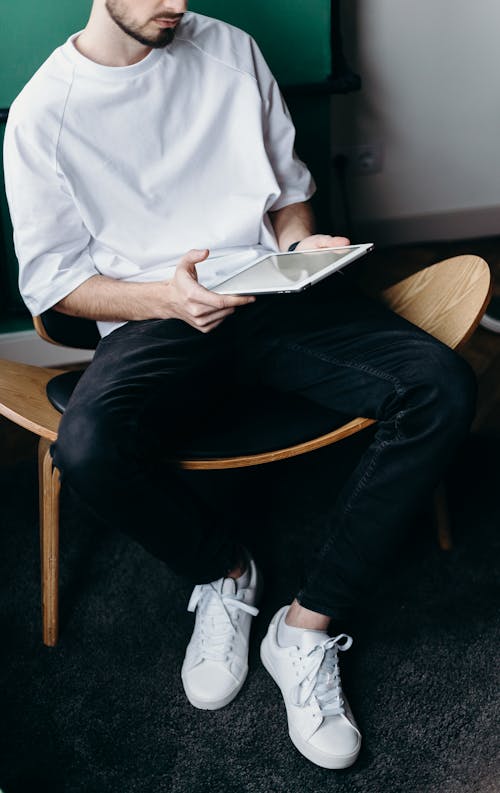 Man in White Shirt and Black Pants Sitting on Brown Wooden Chair