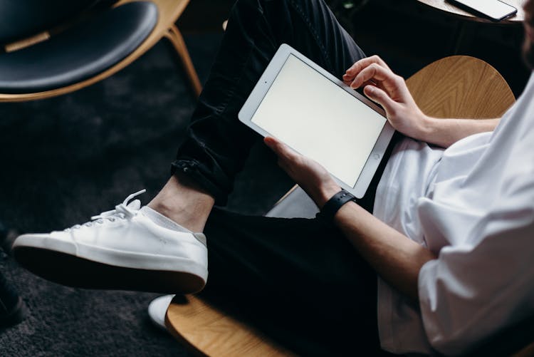 Person In Black Pants And White Shirt Holding White Tablet Computer