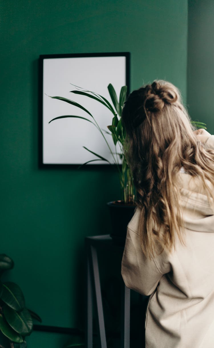 Woman In Beige Hoodie Standing Near Green Wall