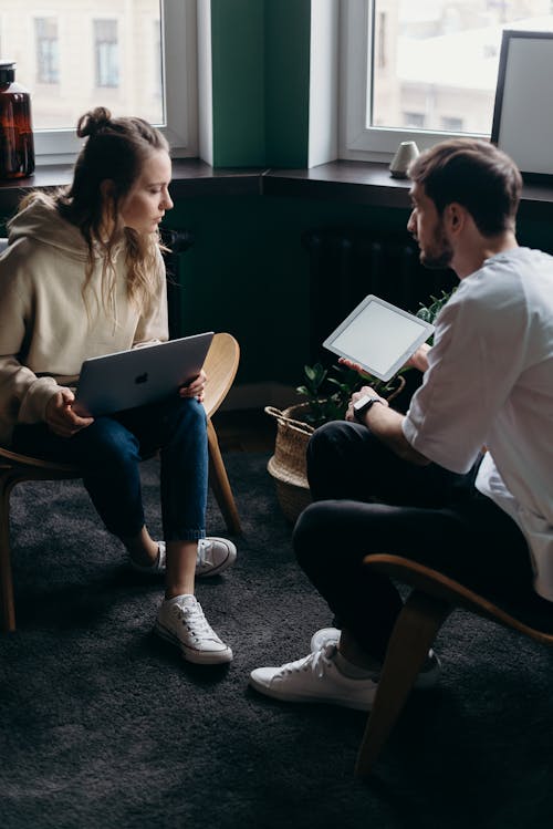 Free Photo of Couple Talking While Holding Laptop and Ipad Stock Photo