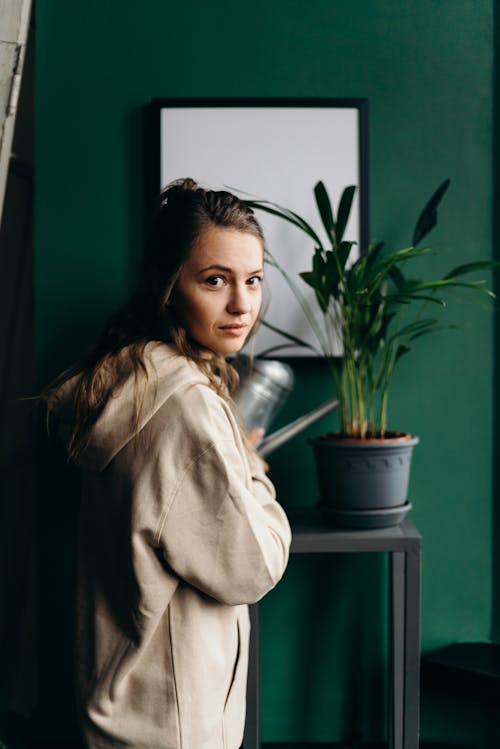 Woman in Beige Coat Sitting Beside Green Potted Plant