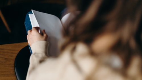 Free Close-up of an adult reading a blank notebook indoors, focused on the pages. Stock Photo