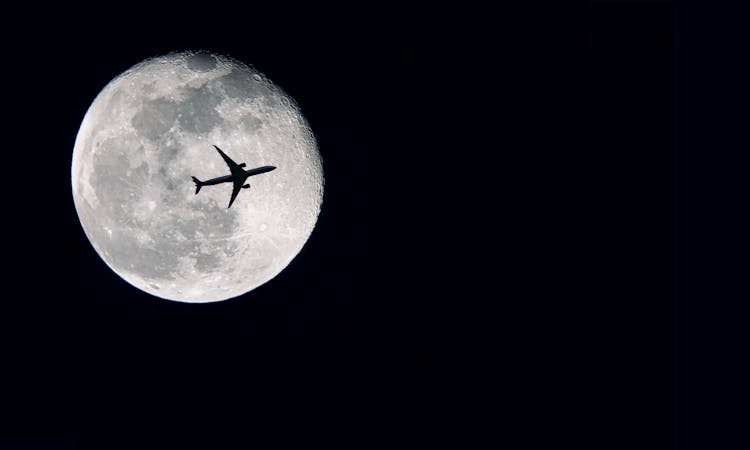 Silhouette Of Airplane In Front Of Full Moon