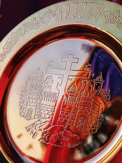 Decorative shiny golden plate with carved orthodox cross and churches and ornamental details