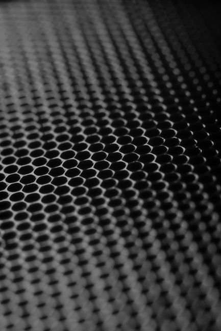 Abstract close-up of a metallic honeycomb grid with a monochromatic tone.