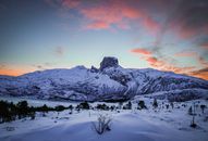 挪威日出时分，白雪覆盖的山脉呈现出壮丽景色，天空充满活力，景观宁静祥和
