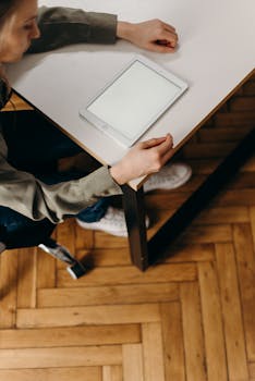 Woman sitting at a desk using a blank-screen tablet for work.